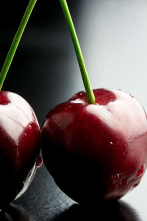 Closeup of delicious red ripe cherry pair with droplets of water.