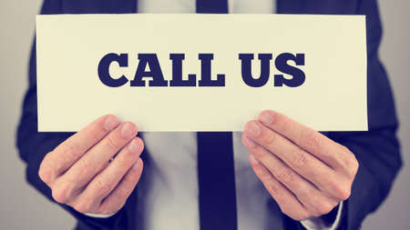 Retro style image of a businessman holding card with Call us sign.の写真素材