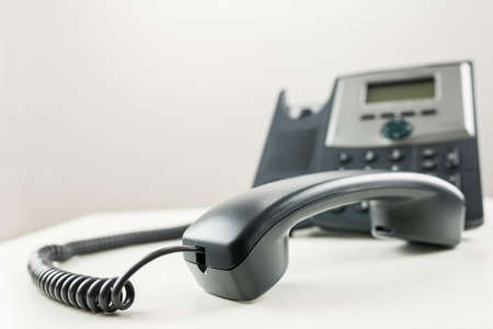Classic black landline telephone with handset off the hook の写真素材