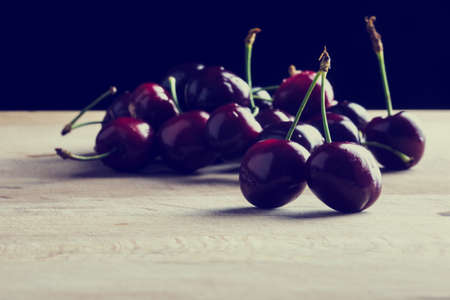 Retro vintage style image of a juicy ripe cherries on a wooden desk.の写真素材