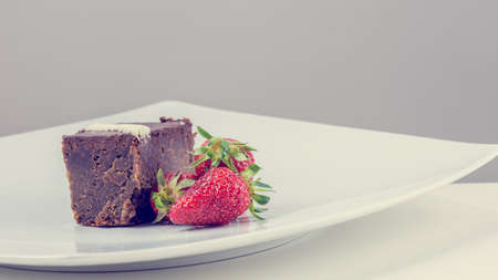 Retro image of pastry and strawberries on a white plate on gray background.の写真素材