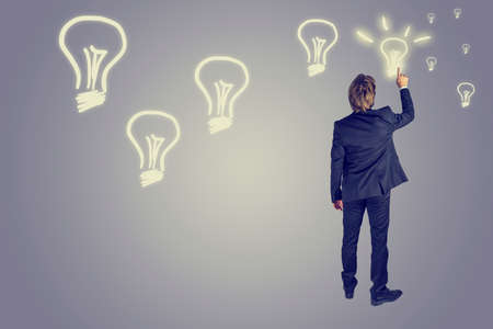 Retro style image of a businessman drawing several light bulbs in the airの写真素材