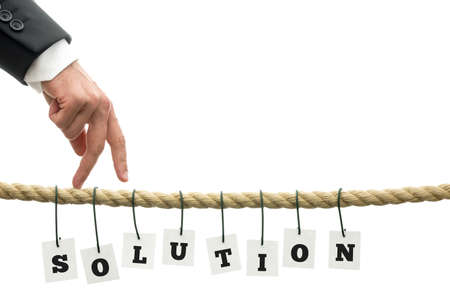 Businessman walking his fingers along a frayed rope wit sign Solution hanging off it. Conceptual of overcoming problems.の写真素材