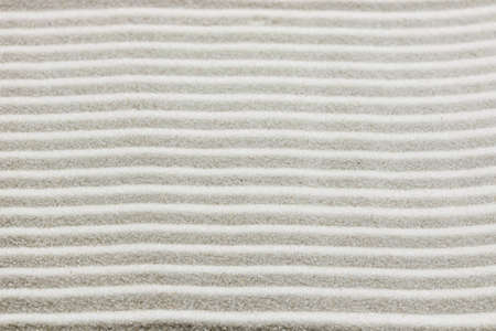 Background pattern of raked white sand in parallel lines in a zen garden in a concept of wellness, spirituality and meditation の写真素材