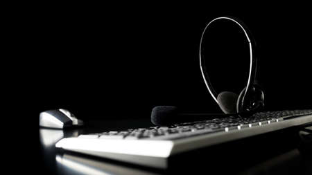 Headset on a computer keyboard in a dark office at night with copyspace conceptual of a call centre, client services, telemarketing or customer support.の写真素材