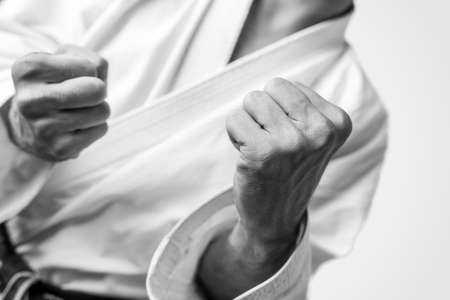 Black and white close up image of the bare fists of a man dressed for martial arts during training or in combat.の写真素材