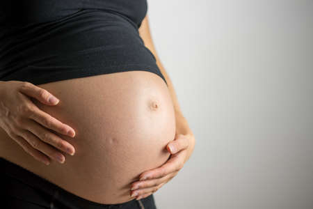 Closeup of pregnant belly in ninth month of pregnancy.