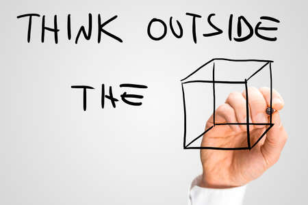 Male hand writing on a virtual screen a creative inspirational message urging to think outside the box.の写真素材