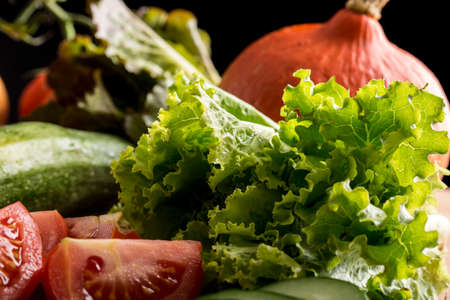 Fresh vegetables and salad ingredients in a kitchen with sliced tomato, leafy green lettuce,...