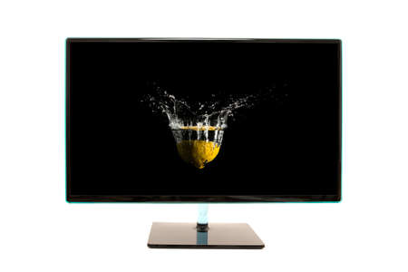 Modern black computer monitor with a motion splash image on the screen of fruit falling into water...