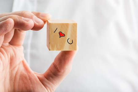 I Love You message on a wooden block with a hand-drawn red heart and text depicting relationships, love, romance, affection and commitment, mans hand over a white shirt with copyspace.の写真素材