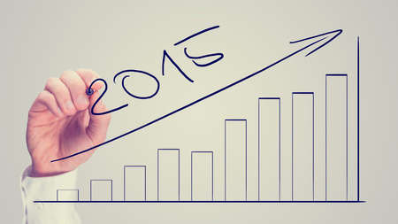 Man drawing an increasing bar graph dated for 2015 on a virtual interface as part of a business plan and strategy projecting increased growth and returns, vintage effect.の写真素材