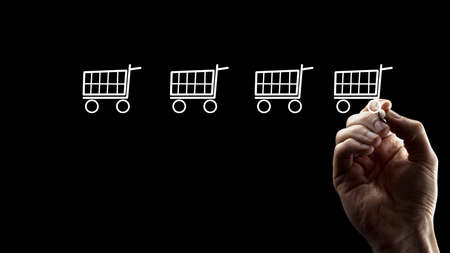 Bare Hand Drawing Small White Shopping Carts, Isolated on Black Background.の写真素材