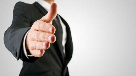 Businessman in Black Suit Showing Handshake Gesture in Close up. Isolated on Gray Background.の写真素材