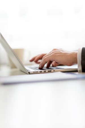 Close up view of the hands of a businessman inputting data on his laptop computer typing on the...
