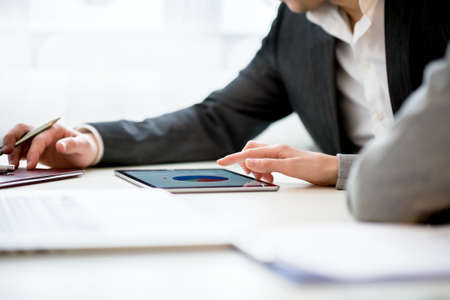 Businesswoman Discussing Business Matters with Her Male Colleague Using Tablet Computer Inside the...