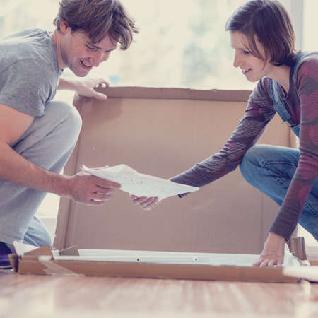 Closeup of young couple looking at a manual of self assembly furniture as they delight in the moving in together. With a vintage style filter effect.の写真素材