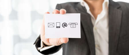 Closeup of businessman showing a white card with contact icons. Conceptual of business information...