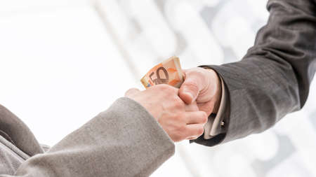 Close up Businessman with Money Handshaking with his Business Partner Inside the Office.