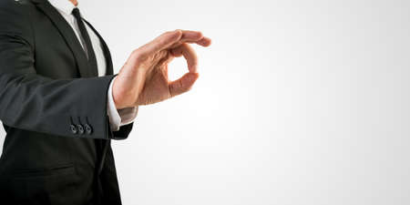 Close up Businessman Showing Conceptual OK Hand Sign on an Abstract Grey Background, Emphasizing Copy Space.の写真素材