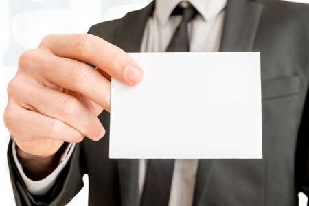 Closeup of businessman showing blank white business card with copy space ready for contact info or other company information.の写真素材