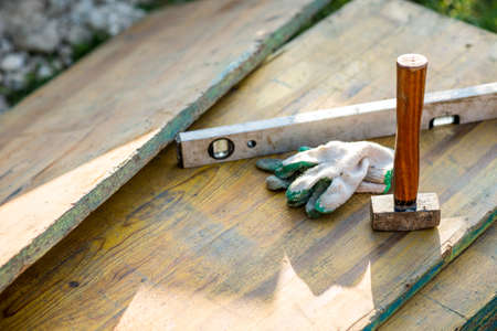 Looking Down at Wooden Mallet, Level and Gloves, Woodworking and Construction Tools on Planks of...
