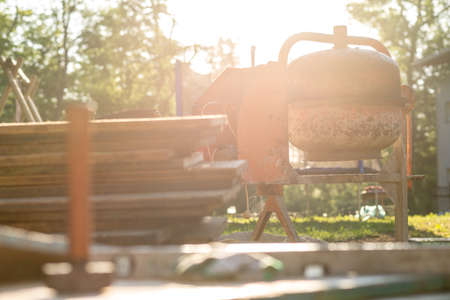 Low Angle View of Building Supplies and Mixer on Construction Site Lit by Bright Sunlight.の写真素材