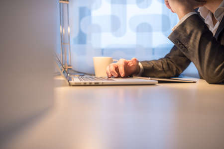 Businessman at his Desk Using his Laptop Computer with a Cup of Coffee on his Side.