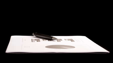 Conceptual Pen on Top of Business Document with Charts Isolated on Black Background, Emphasizing Copy Space.の写真素材