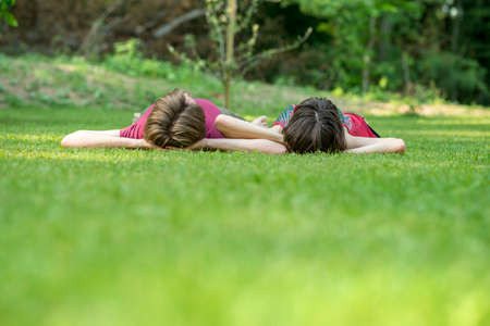 Sweet Couple Lying on the Grassy Ground Outside with Both Hands on their Heads and Facing Up.
