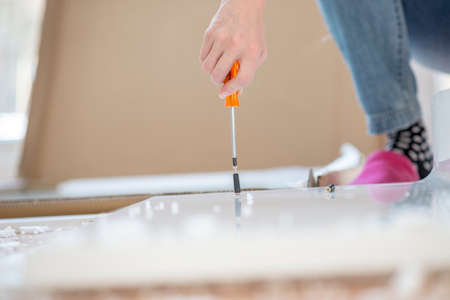 Person assembling newly delivered flat pack furniture with a screwdriver, closeup of the hand with the packaging visible behind.の写真素材