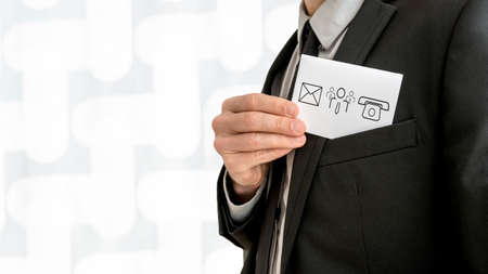 Personal business consultant  removing a business card with communication and people icons - phone, email and contact center icon - from the inner pocket of his jacket, close up view.の写真素材