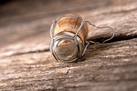 Champagne cork with attached wire and metal cap lying on old weathered cracked wood boards.の写真素材