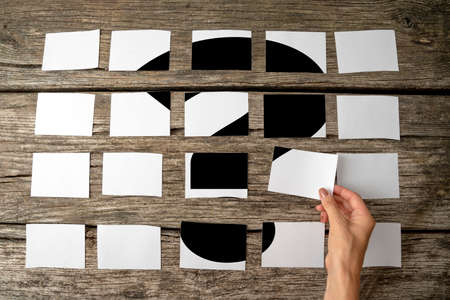 Question or query - solution or answer concept with a woman laying out rows of memo notes with a question mark and placing the last piece in place on the wooden background, close up of her hand.の写真素材