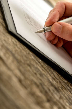 Closeup of male hand signing business contract, application, subscription form  or insurance papers...