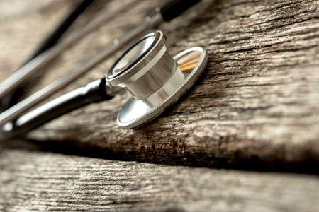 Closeup of medical stethoscope disc on a rustic wooden background.の写真素材