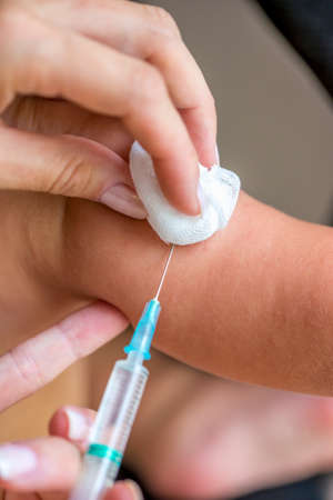 Closeup of female pediatrician vaccinating a baby in his arm with a syringe. Concept of immunization and health care.の写真素材