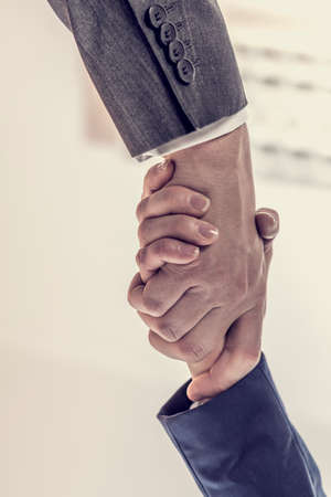 Retro image of business partners - man and woman shaking hands to close a deal, in agreement, greeting or congratulations, view from underneath their hands.の写真素材