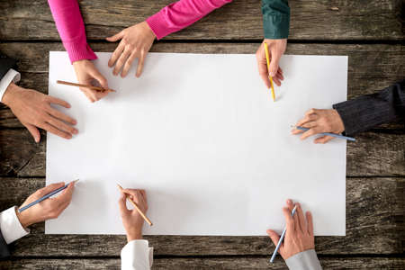 Teamwork and cooperation concept - top view of six people - men and women - drawing or writing on a...
