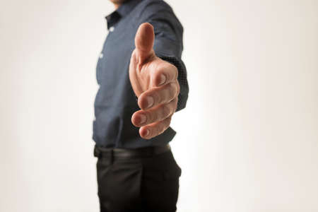 Businessman standing in profile offering you a handshake. Over white background.の写真素材