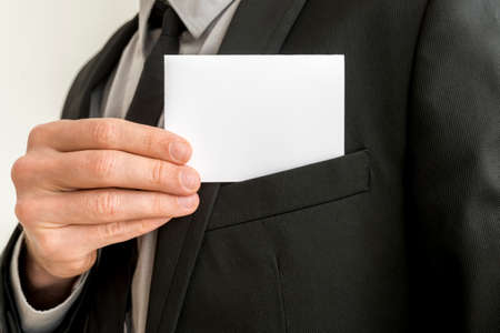 Closeup of businessman removing a blank white business card from the pocket of his elegant suit...