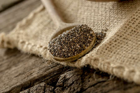 Wooden spoon full of healthy chia seeds lying on a linen textile.の写真素材