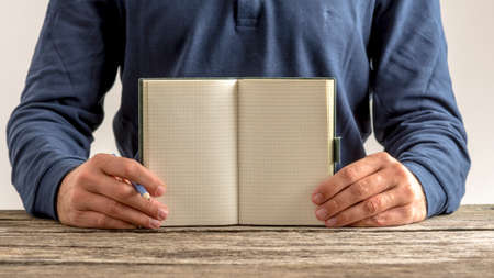 Front view of a man showing an open blank note pad with pencil in his hand. Copy space ready for your message or sign.の写真素材