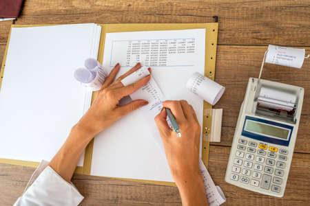Female accountant or tax adviser working with receipts and statistical  data with calculator on her office desk.の写真素材