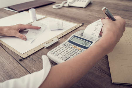 Retro image of accountant or businesswoman balancing the books checking the figures on a ledger with...