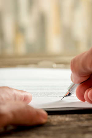 Extreme low angle view on high quality fountain pen in hand writing personal signature on paper.