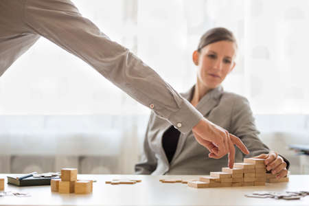 Worker watching someone use fingers on blocks in office for concept about progress and goals.の写真素材
