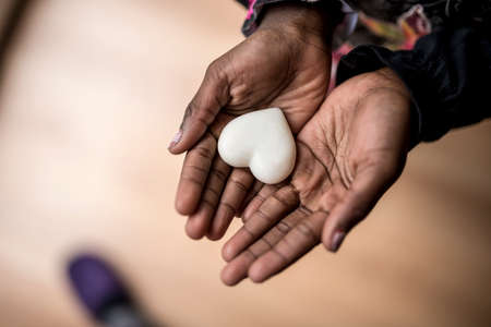 Top view of African-American girl hands holding a marble made heart shape.の写真素材