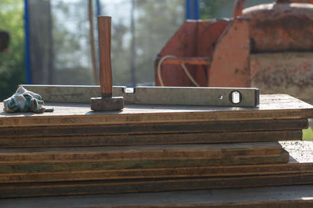 Hammer and spirit level on pile of wooden planks on construction site.の写真素材