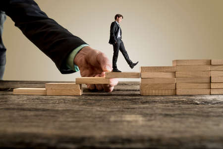 Businessman in business suit walking up steps, while the hand of other man helping him in a conceptual image of insurance, assistance and support.の写真素材